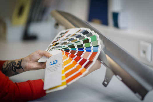 Person hält eine Farbpalette vor eine Zierleiste.JPG